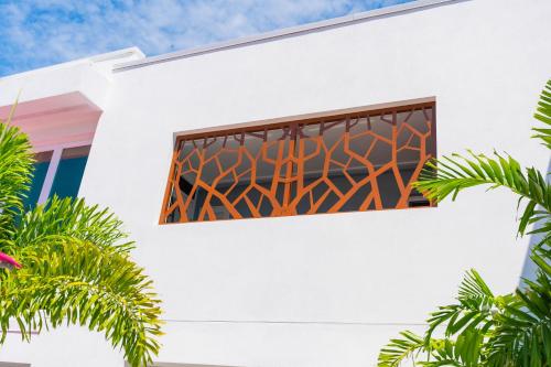 a window on the side of a white building with palm trees at The Saint Hotel in St Pete Beach