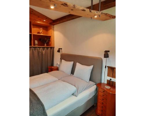 uma cama com lençóis brancos e almofadas num quarto em Living Legends - Tiny House auf den Wiesen der Edermühle em Grosspertholz