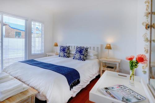 Schlafzimmer mit einem Bett mit blauen Kissen und einem Tisch in der Unterkunft Beach House 11B in Groot Brak Rivier