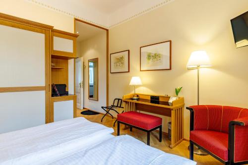 a hotel room with a bed and a desk and a chair at Hotel Herzoghof in Baden