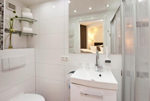 a bathroom with a sink and a toilet and a mirror at City Apart Hotel Füssen in Füssen