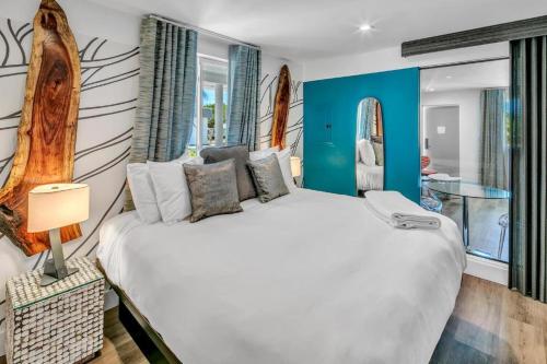 a bedroom with a large white bed with blue walls at The Saint Hotel in St Pete Beach