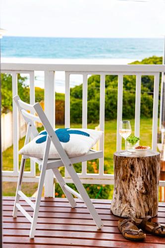 a white chair sitting on a porch with a glass of wine at Beach House 11A in Groot Brak Rivier