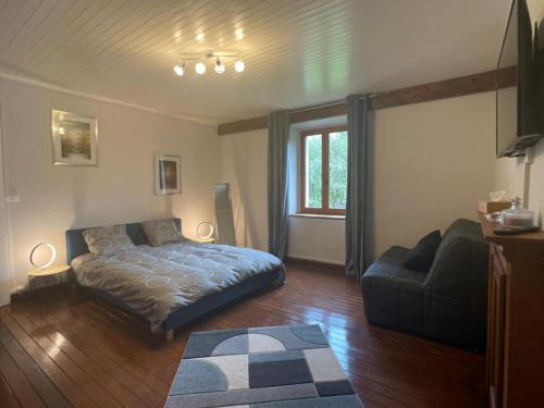 een slaapkamer met een bed, een bank en een stoel bij Gîte Vallée Verte in Burdignin