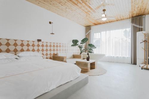 una camera da letto con un grande letto bianco e una vasca di 峨眉山一方民宿Mount Emei Little Place Guesthous a Monte Emei (Emeishan)