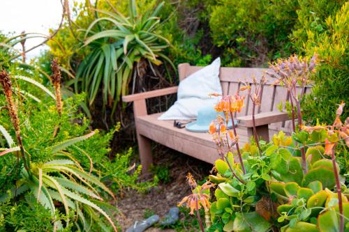 a bench in a garden with flowers and plants at Beach House 11A in Groot Brak Rivier