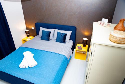 a small bedroom with a blue bed with white sheets and blue pillows at La Stejari Apartment in Suceava