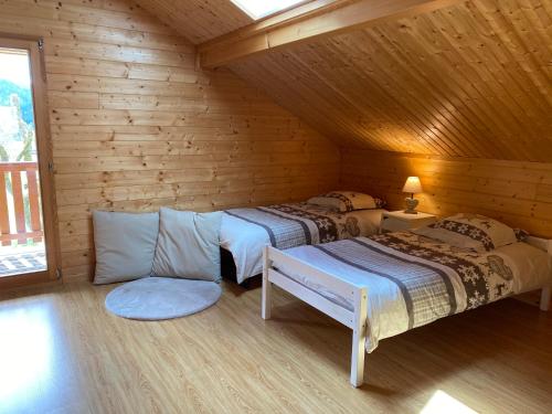 a room with two beds in a log cabin at Le Chalet de la Devinière, bain nordique extérieur chauffé in Xonrupt-Longemer
