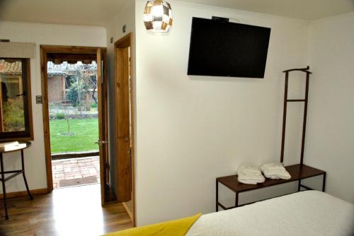 1 dormitorio con 1 cama y TV en la pared en Hotel Boutique Casona Violeta, en San Carlos