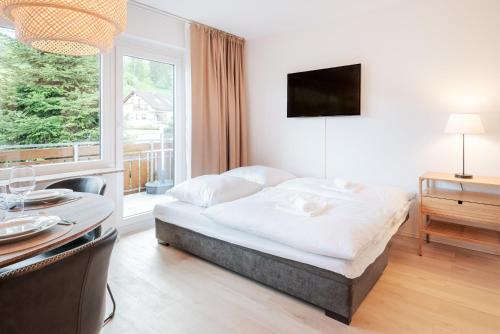 1 dormitorio con cama, mesa y ventana en Ferienwohnung Sonnenglück mit großzügigem Südbalkon, en Lenzkirch