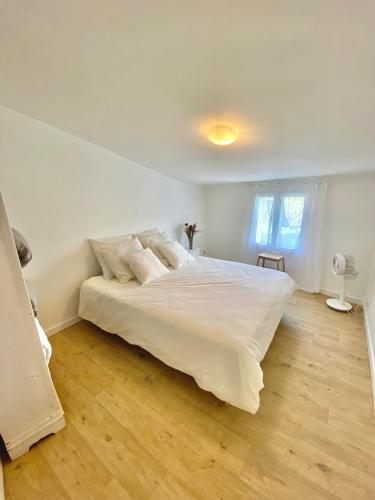 une chambre avec un grand lit blanc et du parquet dans l'établissement Il y a le Soleil, la Campagne et la Mer, à Martigues
