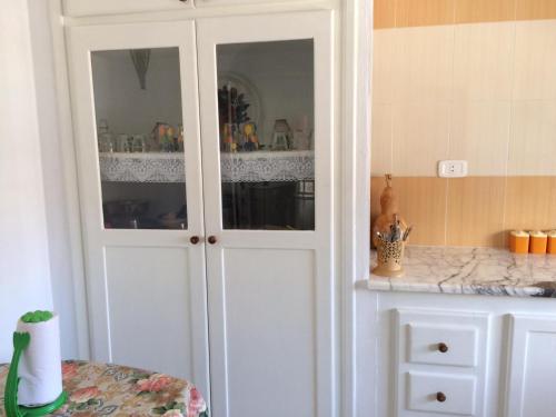 a white cabinet with glass doors in a kitchen at Kélibia Paradise in Kelibia