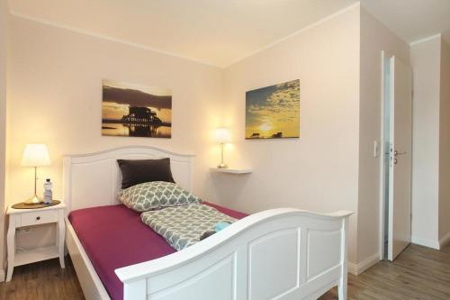 a bedroom with a white bed and two pictures on the wall at Sportpension "Seminarhaus an der Eider" in Tönning