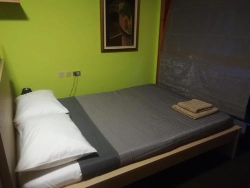 een klein bed in een kamer met groene muren bij casa del lago Lesa in Lesa