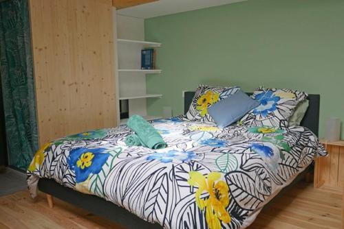 a bedroom with a bed with a floral comforter at chambre d hôte La Grange in Pommiers-en-Forez