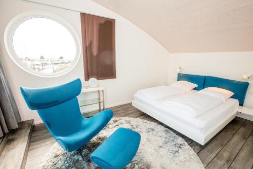 a living room with a bed and a blue chair at KYST 5410 Floating Home 1 in Neustadt in Holstein