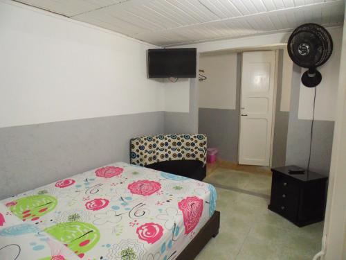 a bedroom with a bed and a chair and a fan at Hotel Ciudad Señora Buga in Buga