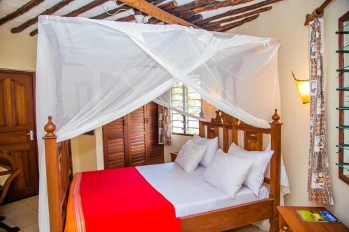 a bedroom with a red and white bed with a canopy at 3 Bed Cottage Sleeps 6- Pool Chef Option Parking in Diani Beach
