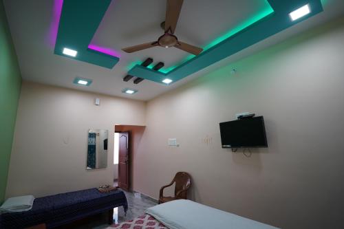 a bedroom with a ceiling fan and a tv at Akash homestay in Hampi
