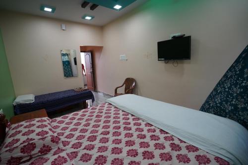 a bedroom with a bed and a tv on the wall at Akash homestay in Hampi