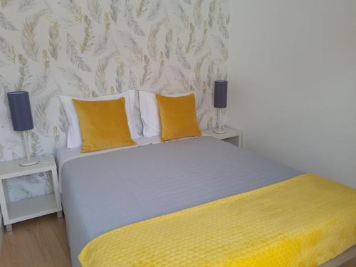 a bedroom with a bed with yellow sheets and two lamps at Palmeira Comfort in Aveiro