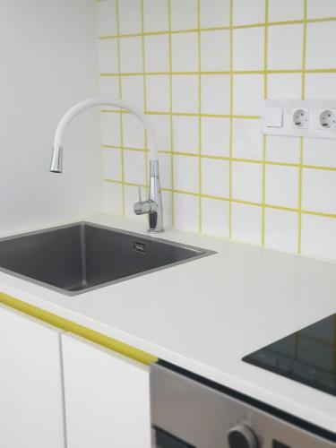 a kitchen with a stainless steel sink and white cabinets at Palmeira Comfort in Aveiro