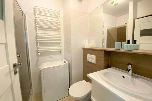 a white bathroom with a toilet and a sink at Homely Apartment in Gdańsk
