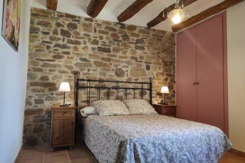 ein Schlafzimmer mit einem Bett und einer Steinmauer in der Unterkunft Casa Escola in Pobla de Segur