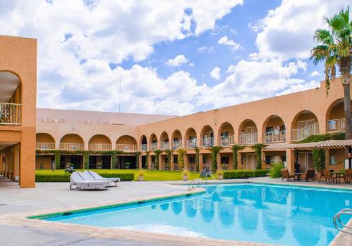 a large building with a swimming pool in a courtyard at Hotel Santa Fe in Camargo
