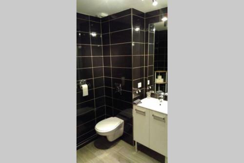 a black tiled bathroom with a toilet and a sink at Appartement T2 terrasse vue mer à 180 in Propriano