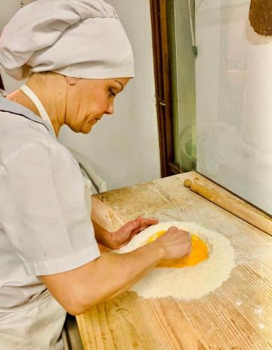 a woman in a kitchen making food on a cutting board at Al Podere del Nonno Romolo in Sansepolcro