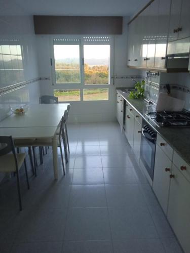 a kitchen with white cabinets and a table in it at La Casa de Vicenta in Arzúa