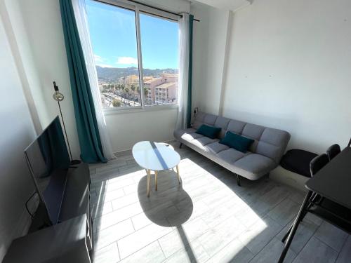 a living room with a couch and a table at Calvi T2 climatisé, wifi, centre-ville, à proximité plage, commerces, taxi & gare, vue plage & montagne in Calvi