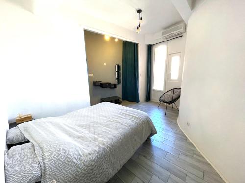 a white bedroom with a bed and a chair at Calvi T2 climatisé, wifi, centre-ville, à proximité plage, commerces, taxi & gare, vue plage & montagne in Calvi