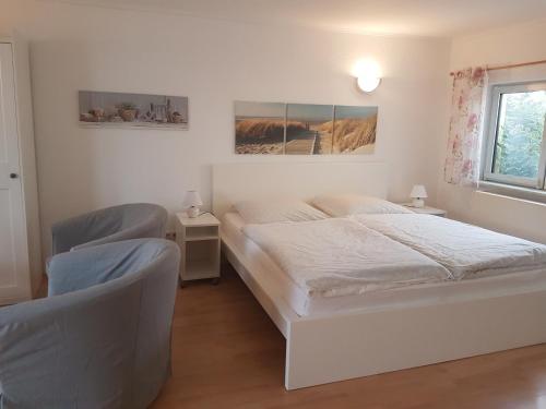 a white bedroom with two beds and a window at Bungalow in Stralsund