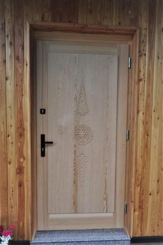 a wooden door with a design on it at Mała Gorczańska Chatka in Ochotnica Dolna