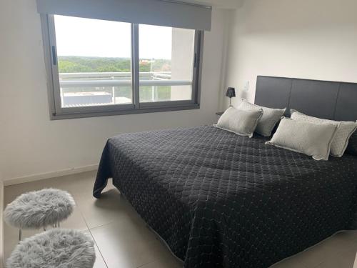 1 dormitorio con 1 cama grande y ventana en Departamento con Amenities en Pinamar