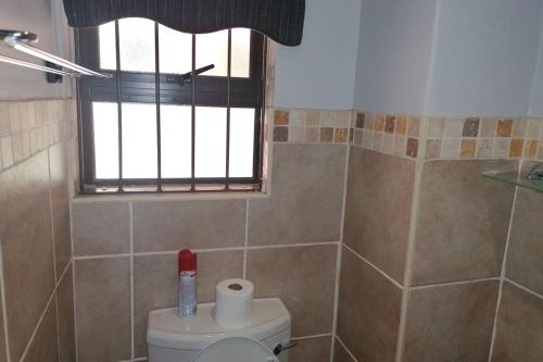 a bathroom with a toilet and a window at BEAUTIFUL APARTM B10 SITUATED IN BAINS GAME LODGE in Bloemfontein