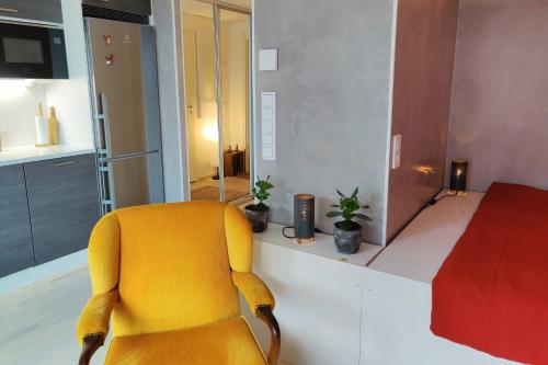 uma cadeira amarela numa sala com um quarto em The Cutest Studio in Central Tampere em Tampere