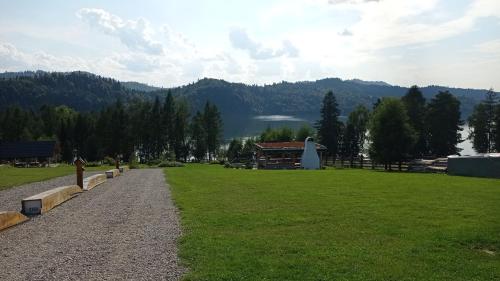a park with a building and a lake in the background at Osada Brzezia in Kluszkowce