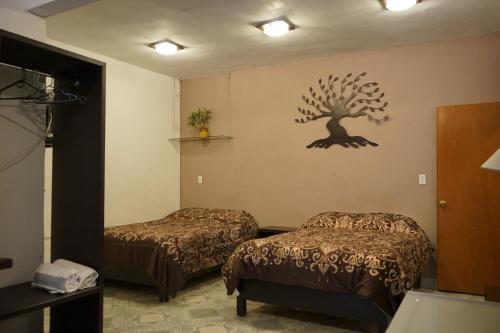 Habitación con 2 camas y un árbol en la pared. en Telpochcalli Hotel & Temazcal, en San Juan Teotihuacán