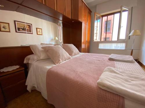 een slaapkamer met een groot bed met witte lakens en een raam bij Apartamento Alonso 1 in Getxo
