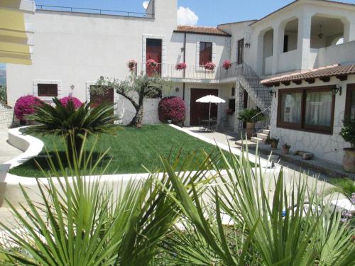 a large white house with a yard with plants at Le Zarafe in Caltabellotta