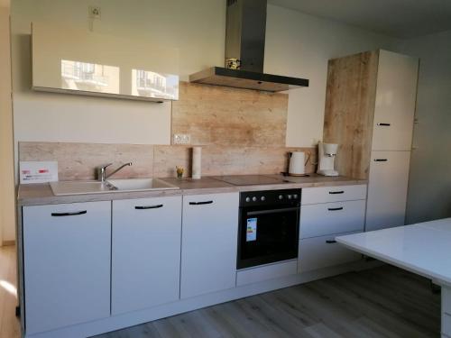 a kitchen with white cabinets and a sink and a stove at Ostseetraum 3 Graal-Mueritz in Gelbensande