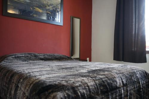 a bedroom with a bed and a red wall at Telpochcalli Hotel & Temazcal in San Juan Teotihuacán
