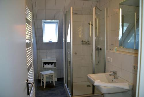 ein Bad mit einer Glasdusche und einem Waschbecken in der Unterkunft Flurstrasse - OG links in Wyk auf Föhr