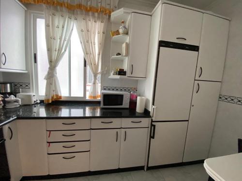uma cozinha com armários brancos, um frigorífico e uma janela em Apartamento Alonso 1 em Getxo