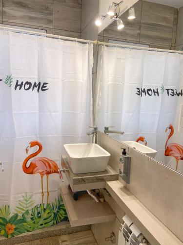a bathroom with a sink and a shower curtain with flamingos at La Pedrera Apart in Villa María