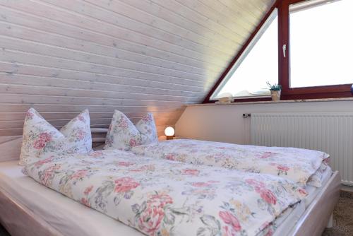 ein Schlafzimmer mit einem Bett mit Kissen und einem Fenster in der Unterkunft Schleswig-Holstein Whg 05 DG in Nieblum
