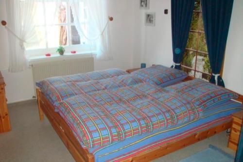 a bedroom with a bed with a blue comforter and a window at Ferienwohnung Biernat in Prinzenmoor